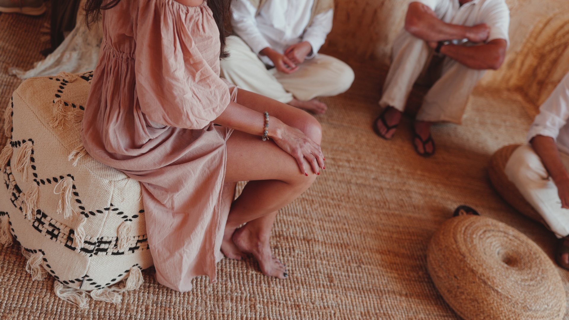Guests gathered in a meditation circle, seated on woven cushions in soft natural light